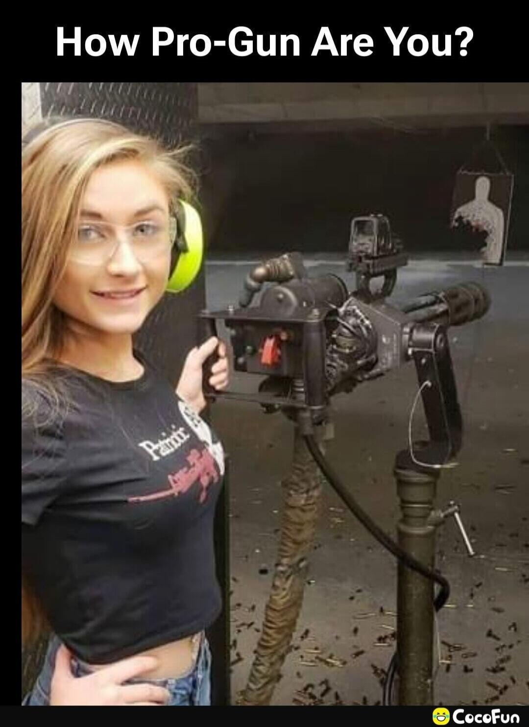 How Pro-Gun Are You? A young woman smiles at the camera while holding a large, mounted firearm, possibly a minigun, at an indoor shooting range. Spent casings are scattered on the floor, and a heavily shot target is visible in the background.