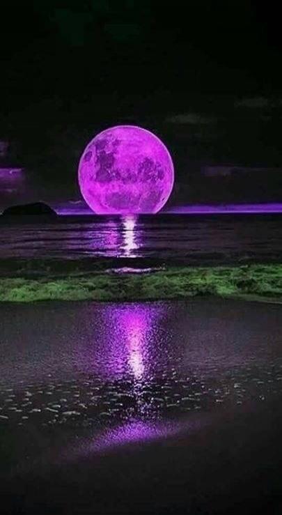 Purple moon over water at night