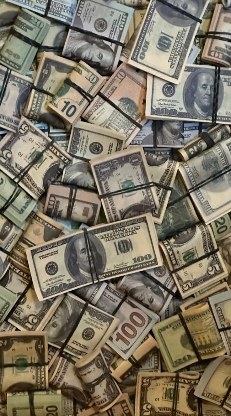 Bundles of US dollar bills in various denominations, including 100, 20, 10, and 5 dollar notes. The text 'ONE HUNDRED DOLLARS', 'TWENTY DOLLARS', 'TEN DOLLARS', 'FIVE DOLLARS', 'UNITED STATES OF AMERICA', and 'WE TRUST' is visible on the currency.