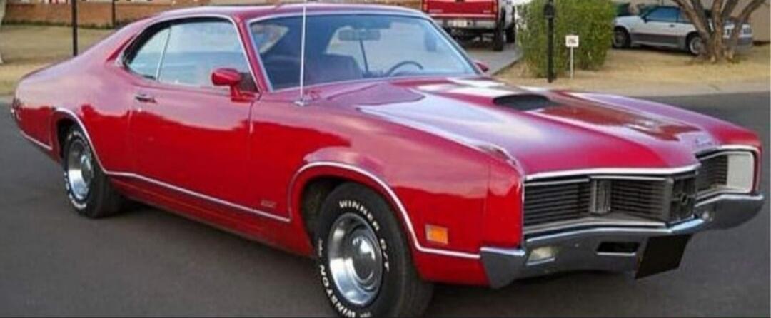 Red vintage muscle car (approx. 1970s) parked outdoors.