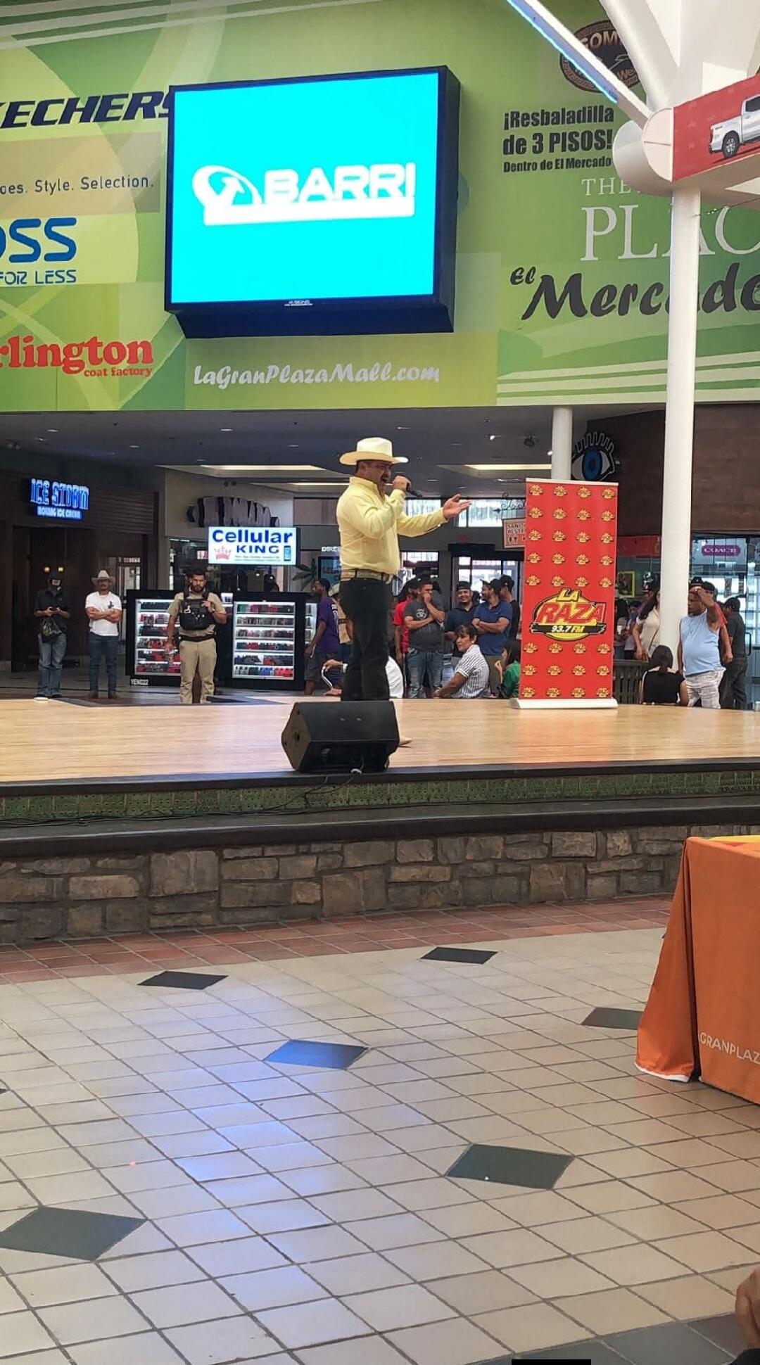 SKECHERS, ROSS FOR LESS, Burlington coat factory, LaGranPlazaMall.com, BARRI, THE PLAZA, ICE STORM BOUNCING ICE CREAM, CELLULAR KING, LA RAZA 93.7 FM, GRANPLAZA. A man is speaking on a stage with a microphone at what appears to be a mall event.