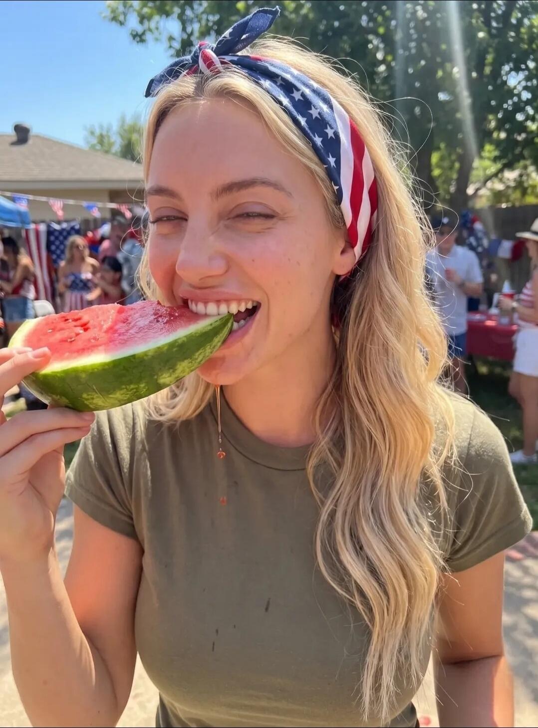 A blonde woman with an American flag patterned headband is smiling and eating a slice of watermelon, with juice dripping down. She is wearing a green t-shirt. In the background, there are people and American flags, suggesting a festive outdoor gathering.