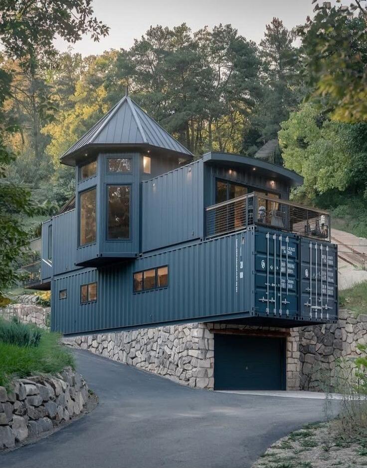 Container house built from stacked shipping containers on a hillside.