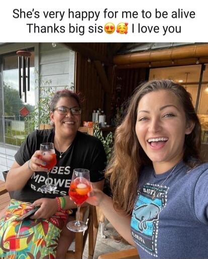She's very happy for me to be alive. Thanks big sis. I love you. Two women are smiling and toasting with drinks.