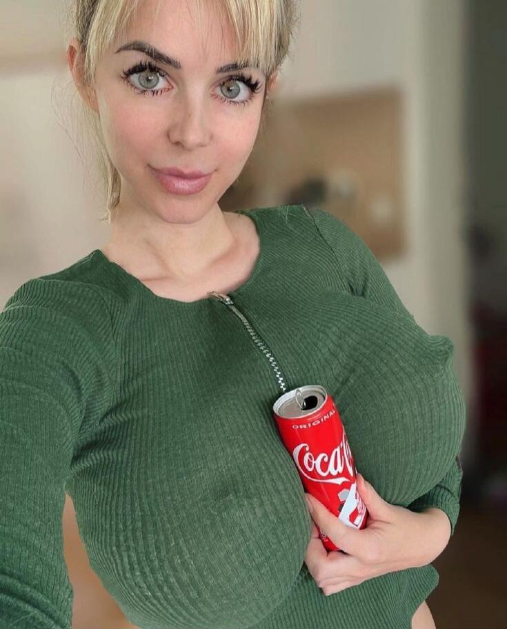 Coca-Cola can held against a green top. The person is posing for a selfie.