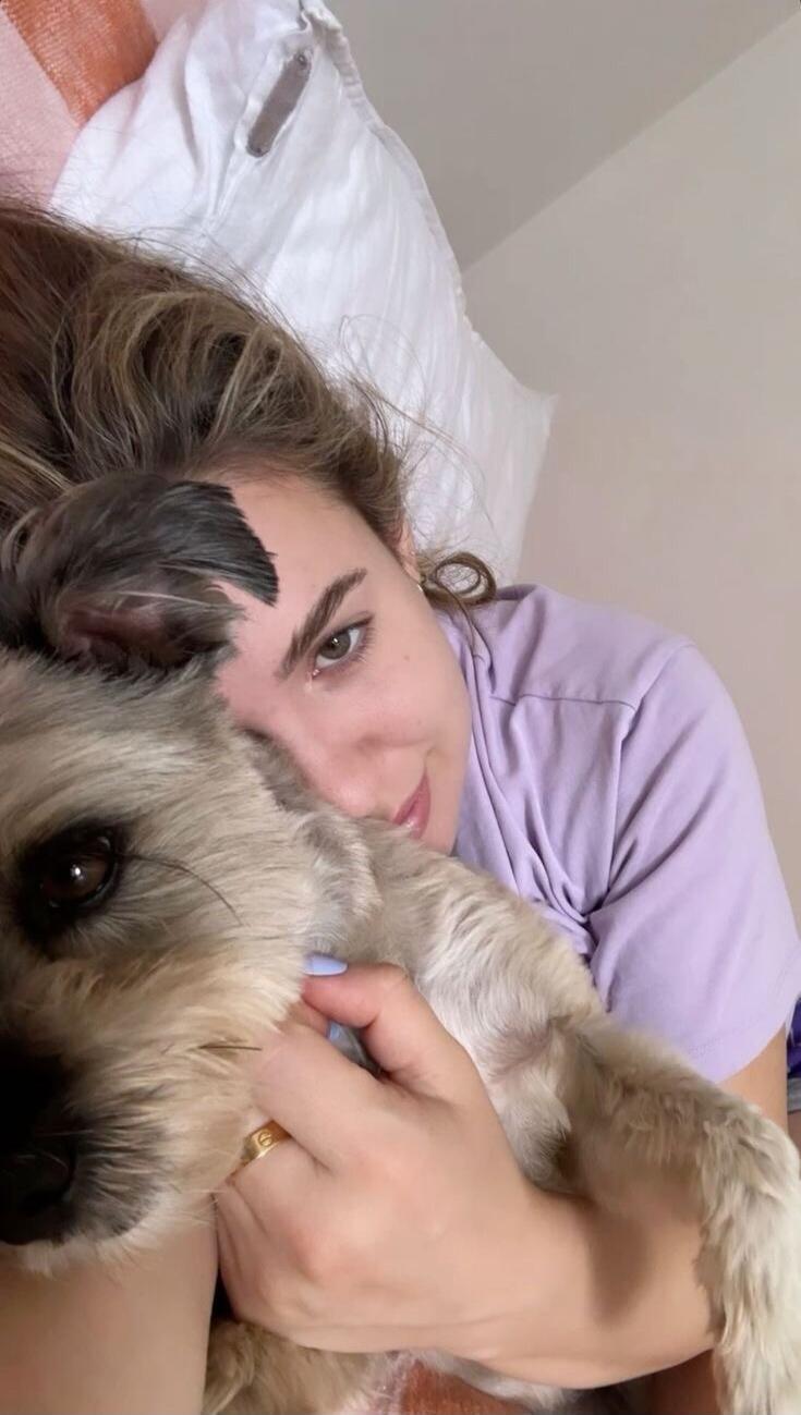 Photo of a person lying in bed cuddling a small dog.