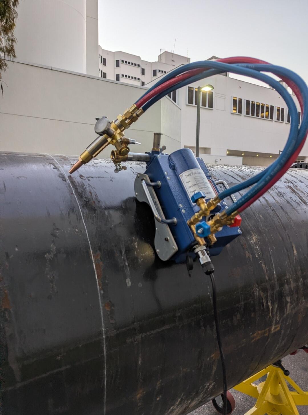 A steel pipe cutting machine, model CAS-100, with a cutting speed of 100-400 mm/min and power 100K, is attached to a large black pipe.