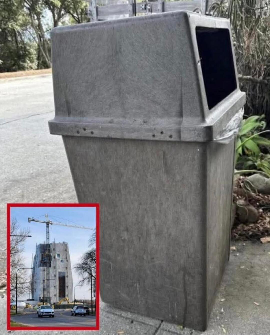 A large gray outdoor trash bin on a sidewalk with a small inset image of a construction site showing a tall building and a crane.