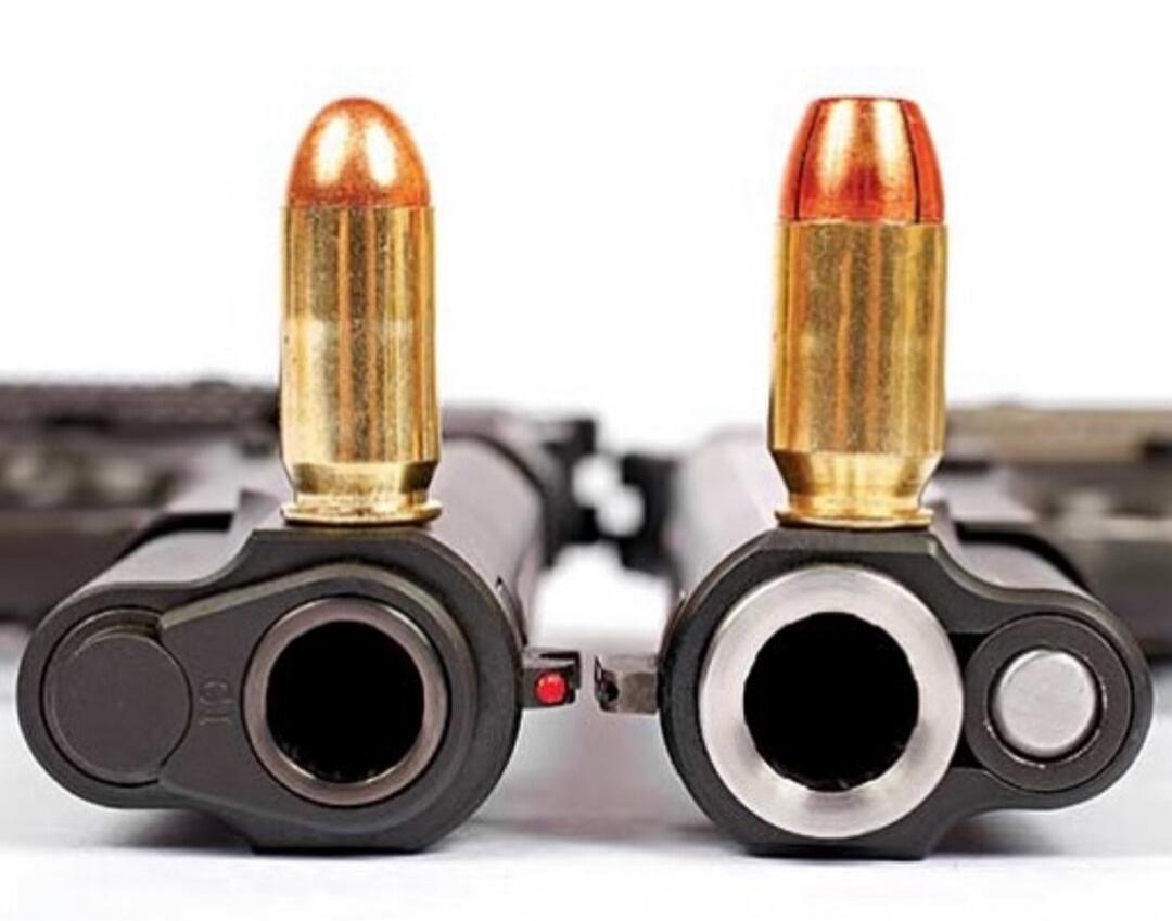 Close-up of two handgun barrels with bullets standing upright on top.