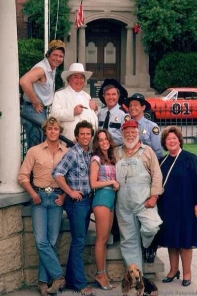 The Dukes of Hazzard cast photo with the General Lee car in the background.