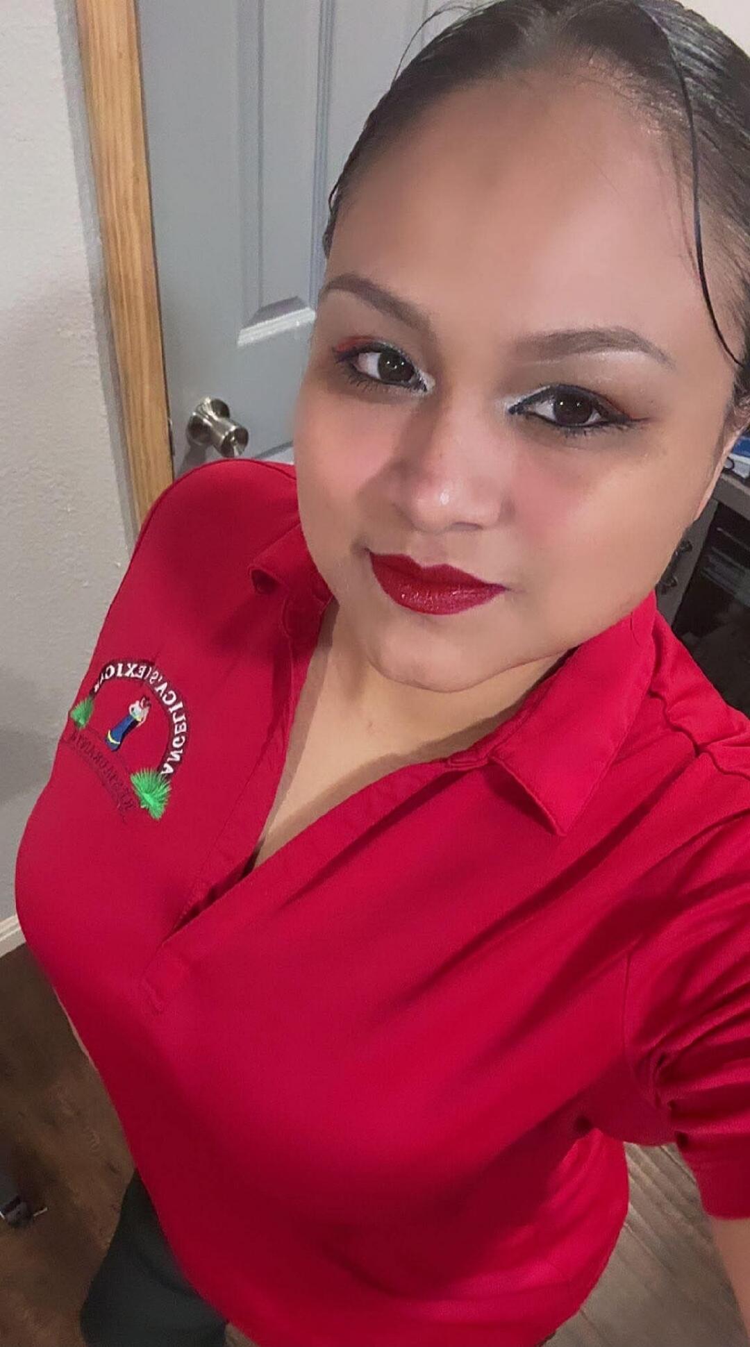 Portrait of a woman wearing a red polo shirt with an embroidered logo on the left chest.