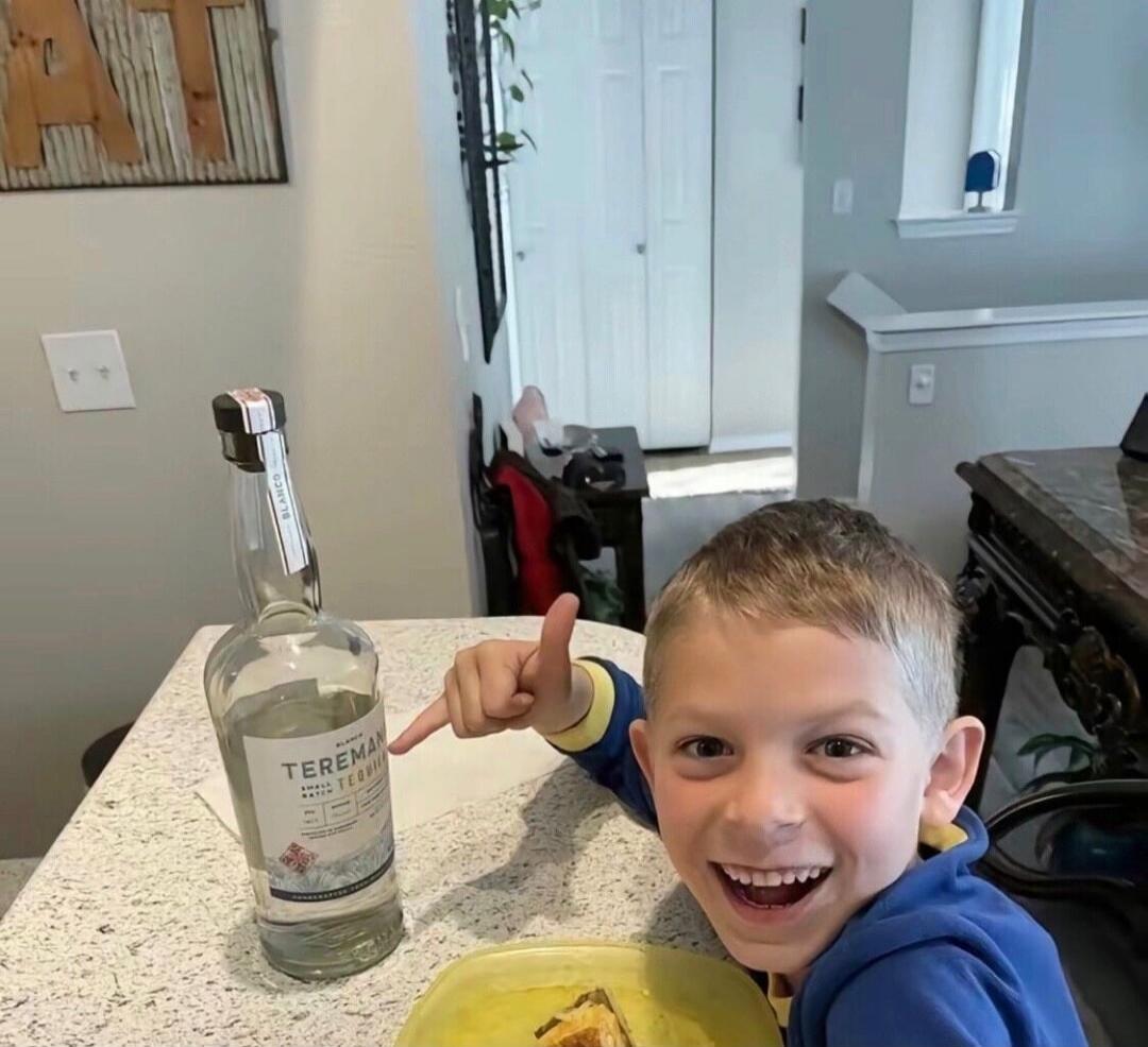 A bottle labeled 'TEREMA' on a kitchen counter near a smiling boy. The boy is wearing a blue hoodie and pointing at the bottle.