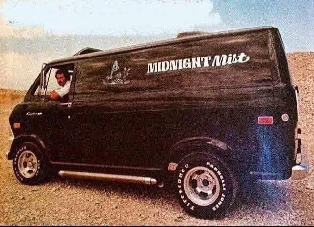 A man is driving a black custom van with 'MIDNIGHT Mist' written on its side. The tires have 'PARNELLI JONES' and 'FIRESTONE' visible. The van is in a desert-like setting under a light sky.