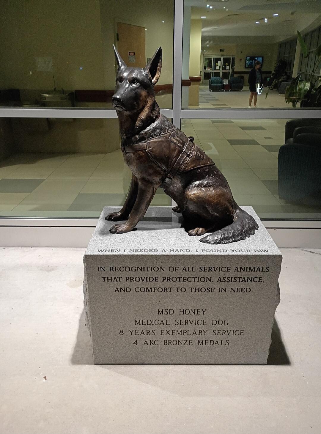 WHEN I NEEDED A HAND, I FOUND YOUR PAW. IN RECOGNITION OF ALL SERVICE ANIMALS THAT PROVIDE PROTECTION, ASSISTANCE, AND COMFORT TO THOSE IN NEED. MSD HONEY, MEDICAL SERVICE DOG, 8 YEARS EXEMPLARY SERVICE, 4 AKC BRONZE MEDALS. (Text on dog's vest: MAYOR 24 SERVICE DOG)