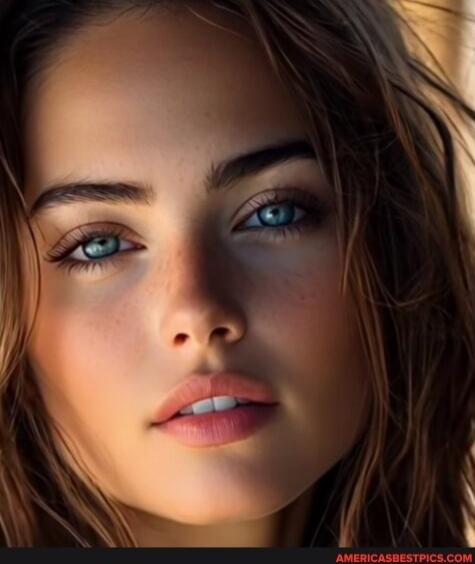 Close-up portrait of a young woman with blue eyes, brown hair, soft lighting.