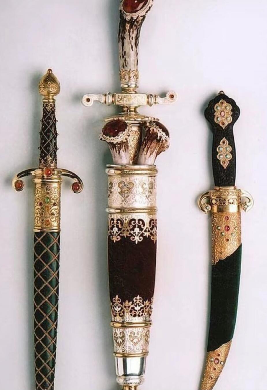 Three ornate ceremonial daggers/swords with intricate gold and jewel embellishments, sheaths, and curved blades.