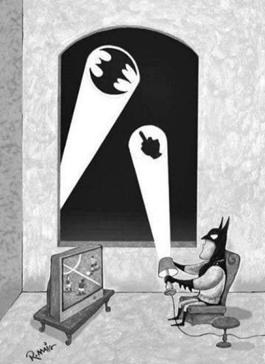 Batman is sitting in a chair, watching a basketball game on TV. He is holding a lamp that projects a middle finger symbol onto the wall, while the Bat-Signal is visible through a window above.