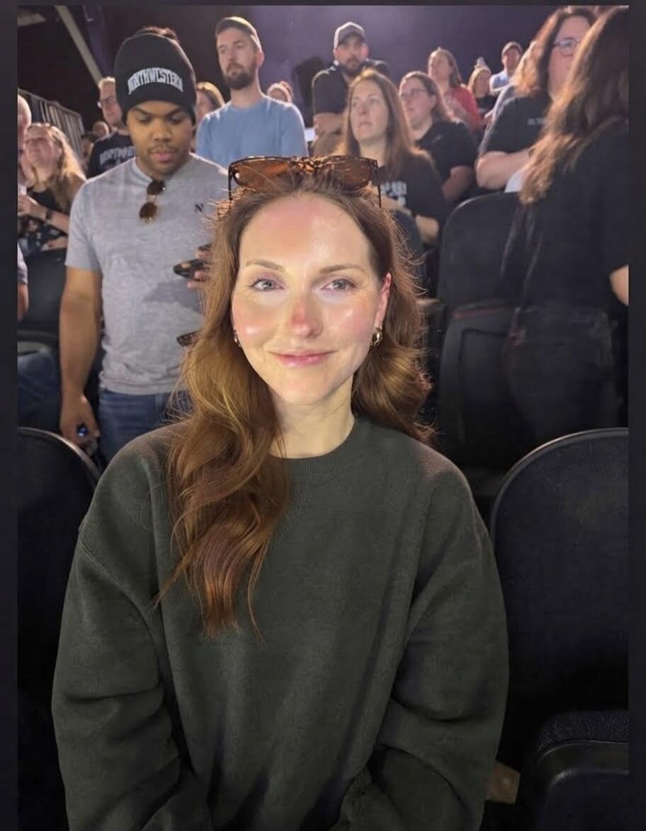 A woman smiling at the camera in a crowd. Text visible on a beanie: NORTHWESTERN.