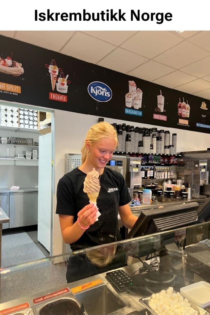 Iskrembutikk Norge. Kjöris. TRUDAIS. BRAGDAREFUR. OREO SHAKE. SMOOTHIE. BANANA SPLIT. A young woman, likely an employee, is smiling and holding an ice cream cone in an ice cream shop. Various ice cream and drink options are displayed on the wall.