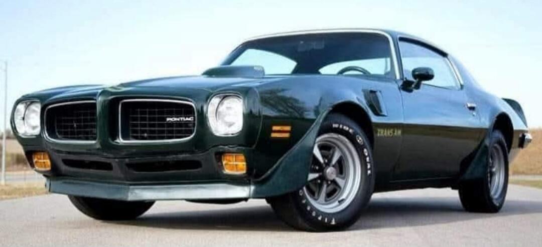 Green classic muscle car, Pontiac Firebird Trans Am, low-angle shot on open road.