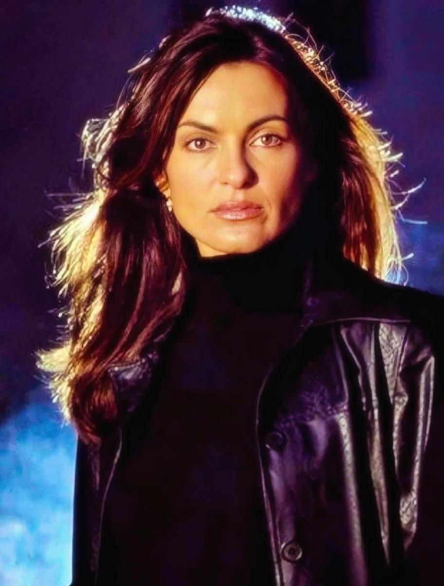 Portrait of a woman with long dark hair wearing a black turtleneck and a black leather jacket.