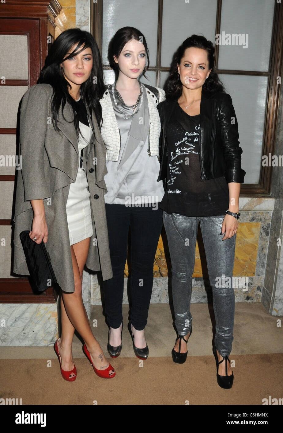 Three women posing for a photo at an event. The woman on the right has text on her t-shirt that reads: 