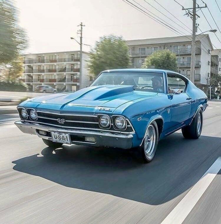 SS 396 USA1. A classic blue muscle car, a Chevrolet Chevelle SS, is driving on a sunny street.
