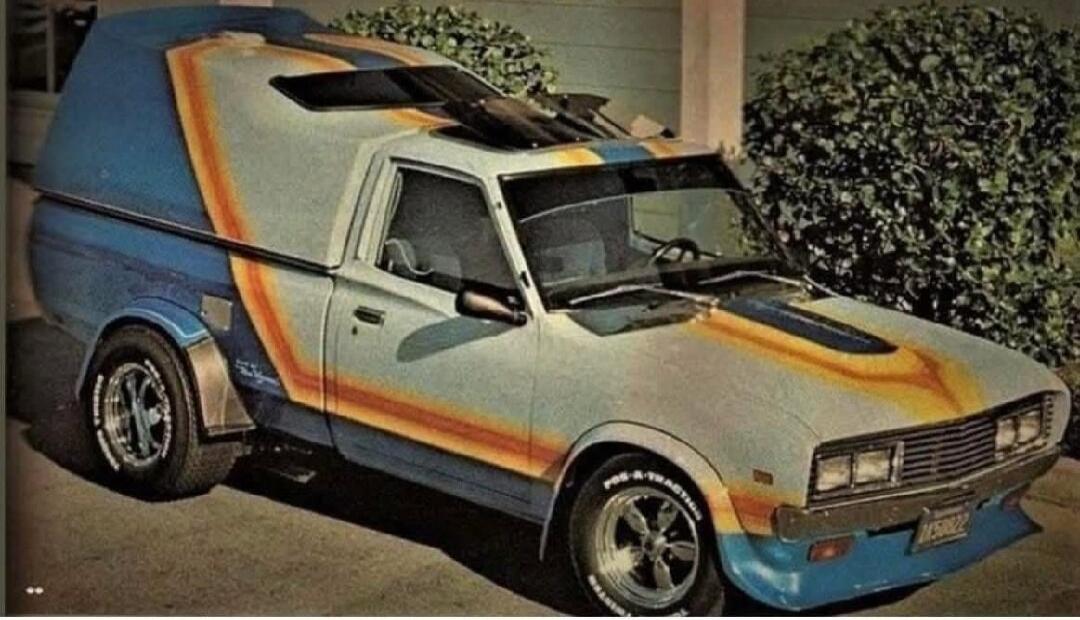 A customized vintage van with bright orange and blue paint and a unique body kit.