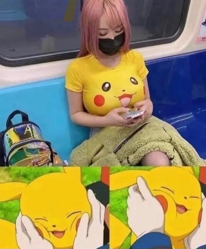 Photo of a person wearing a yellow Pikachu shirt on a train, wearing a black mask.