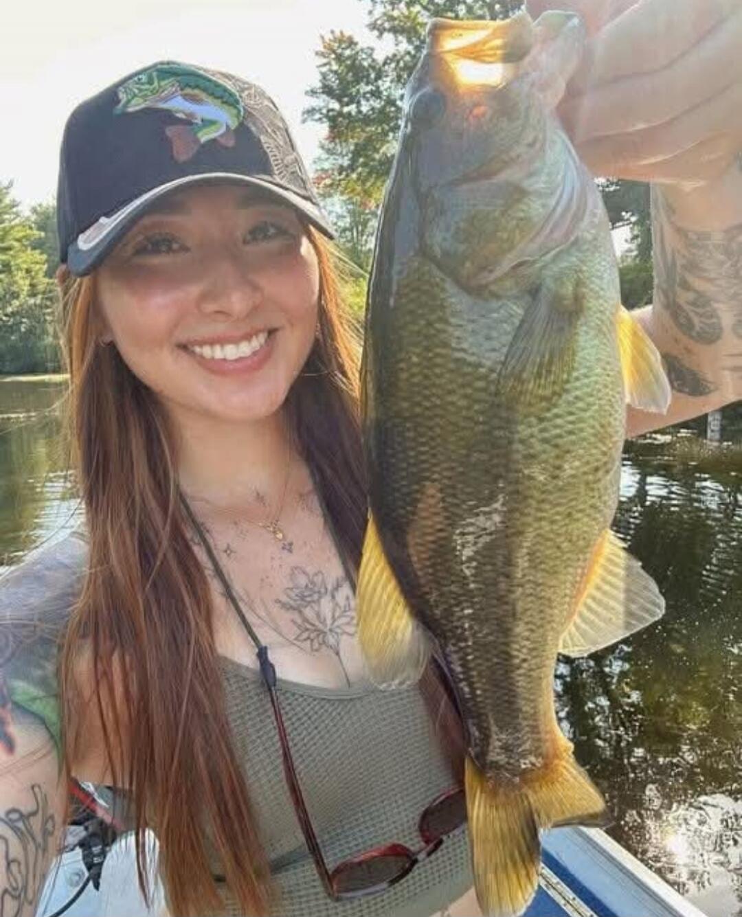 A woman holding a large fish on a boat outdoors.