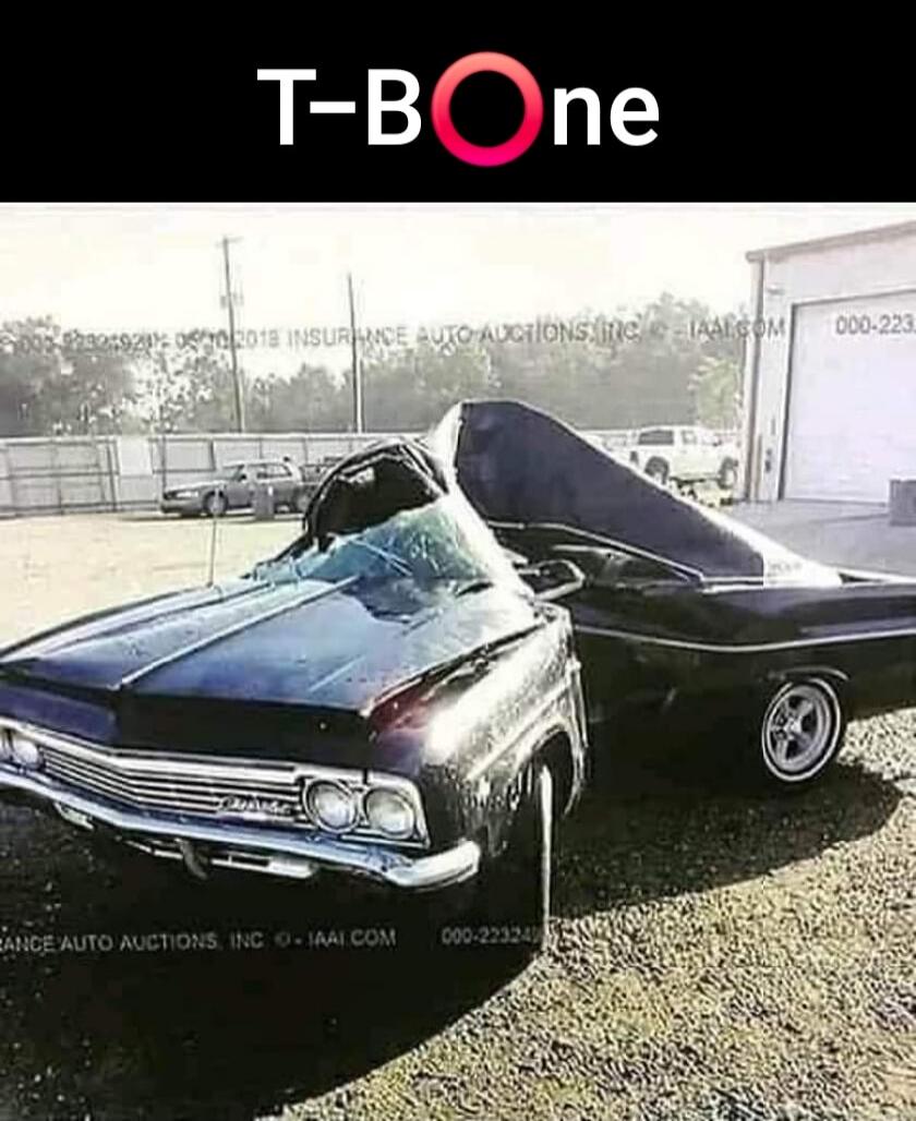 T-BOne. INSURANCE AUTO AUCTIONS, INC. - IAAI.COM. A severely damaged black classic car, appearing to be split in half or folded in an unusual way, resembling a T-bone steak, in what looks like an auto auction or salvage yard.