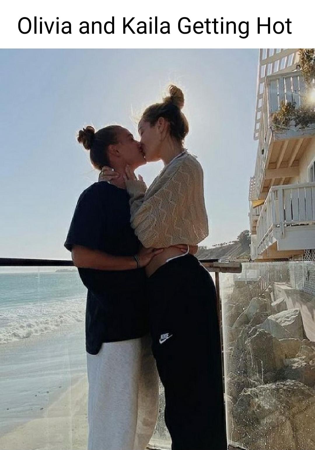 Olivia and Kaila Getting Hot. Two women are kissing on a balcony overlooking the ocean.