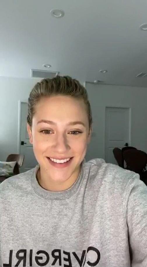 A woman smiling at the camera, wearing a grey sweatshirt with 'COVERGIRL' text on it.