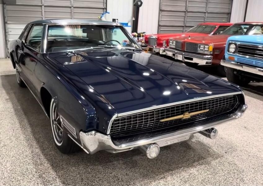 Chevrolet emblem on grille; classic dark blue car in a showroom with other vintage cars.