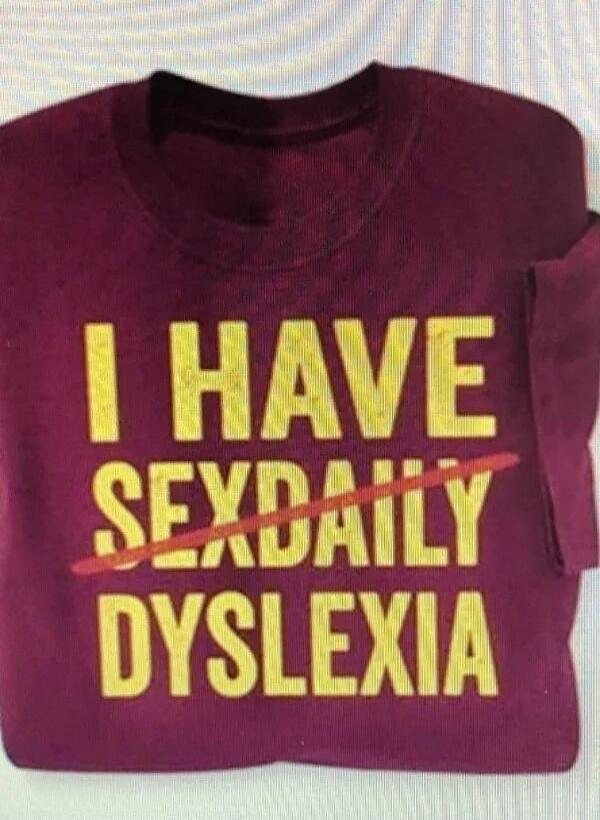 The text on the burgundy t-shirt reads: 'I HAVE SEXDAILY DYSLEXIA', with the word 'SEXDAILY' crossed out by a red line. The humor comes from the suggestive misspelling and the play on words related to dyslexia.