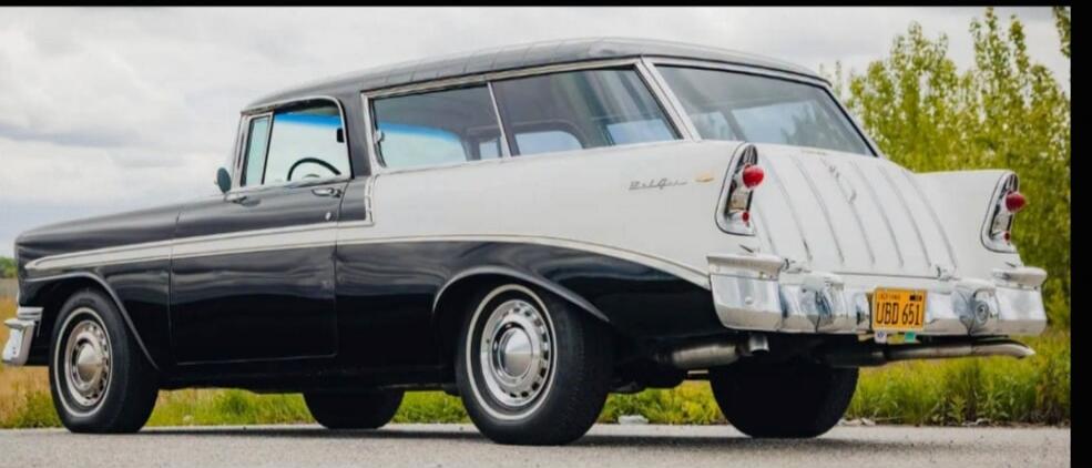 A classic black and white two-door station wagon, resembling a 1957 Chevrolet Bel Air Nomad, with license plate UBD 651.