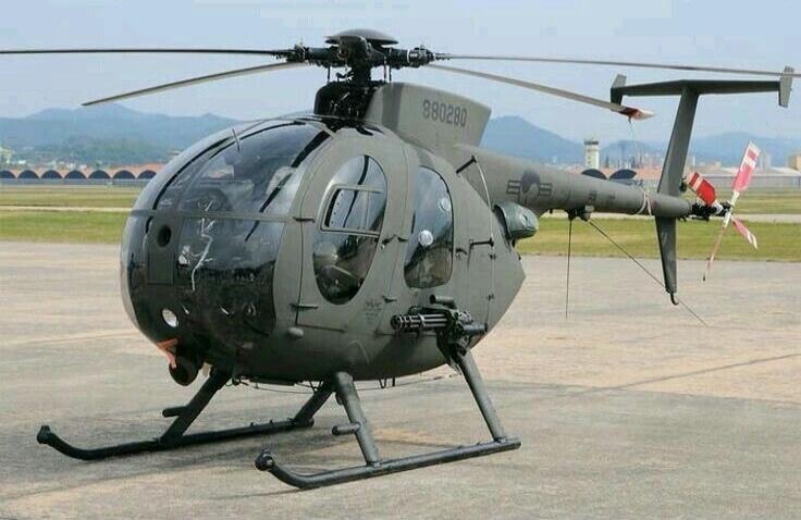 A gray military helicopter parked on a runway or tarmac.