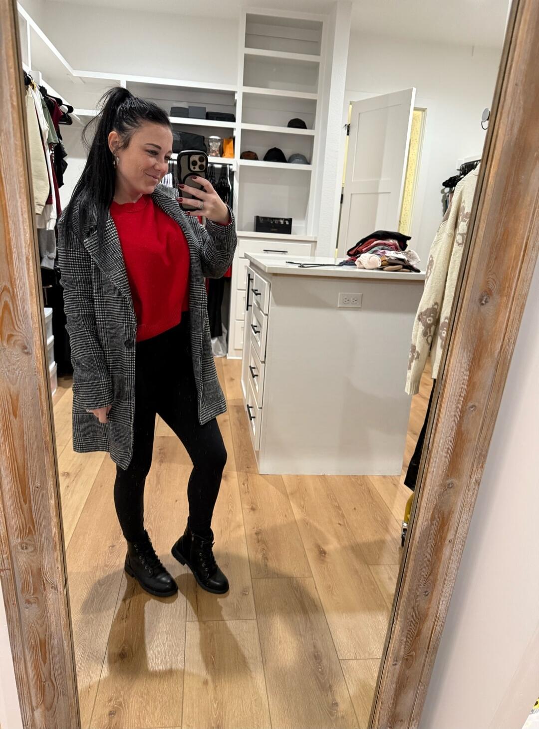 Session ID: 1031094.
A person is taking a mirror selfie in a walk-in closet. They are wearing a red top, a gray checkered coat, black pants, and black combat boots. The closet has open shelves and a central island with drawers.