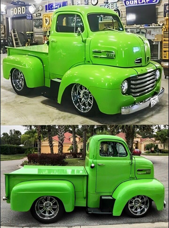 A bright green vintage Ford pickup truck, customized with a lowered suspension and chrome wheels. Signs visible include 'FORD' and 'DUNLAP'S', and 'V8' on the truck's side.