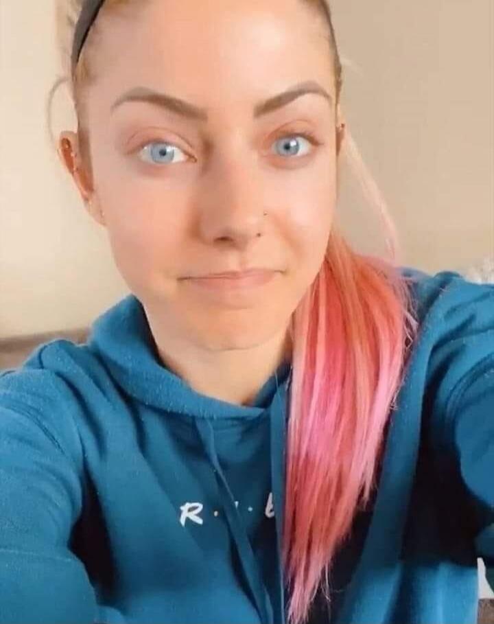 Selfie of a woman with blue hoodie and pink hair.