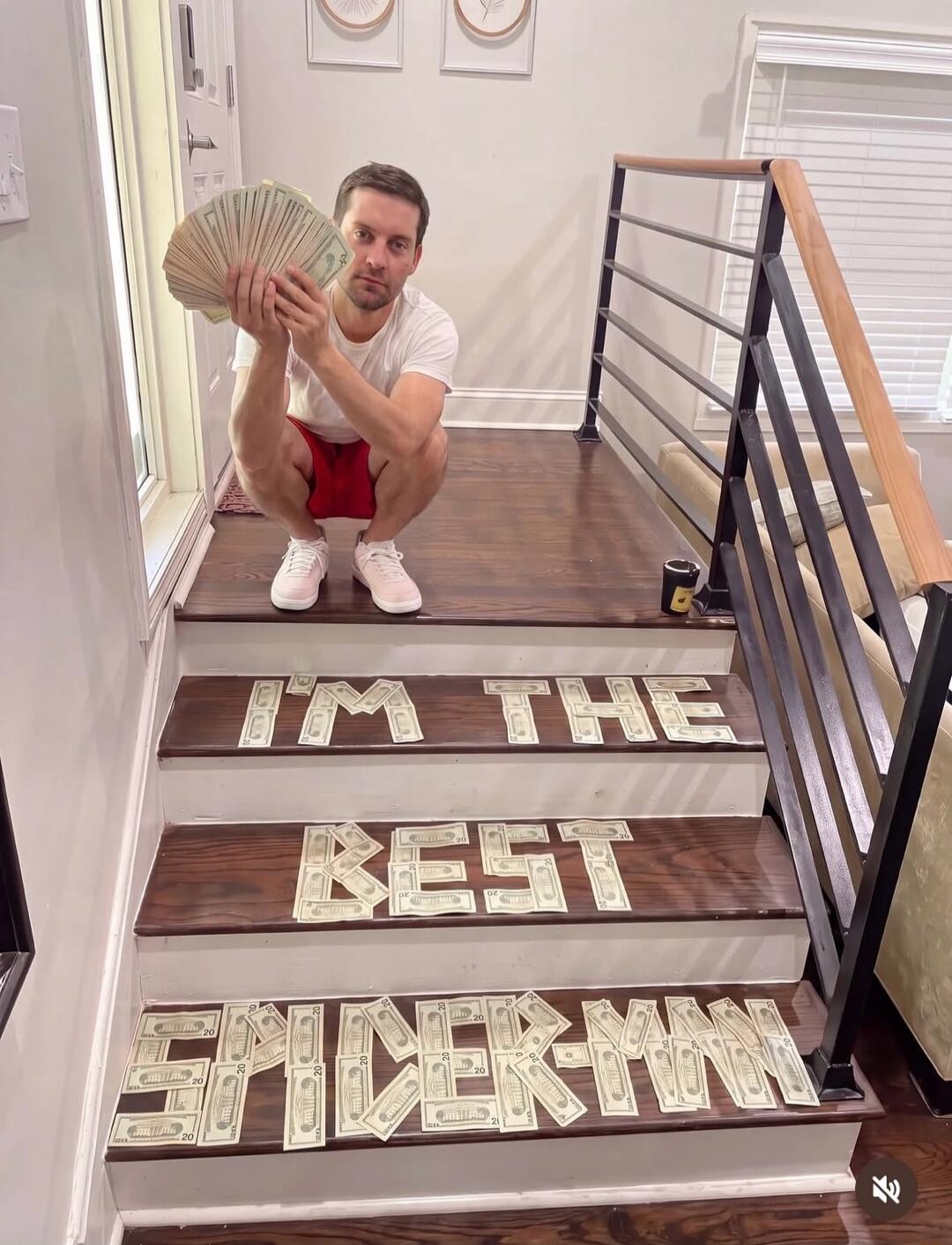 Tobey Maguire holding a fan of money, with the words 'I'M THE BEST SPIDER-MAN' spelled out in money on the stairs.