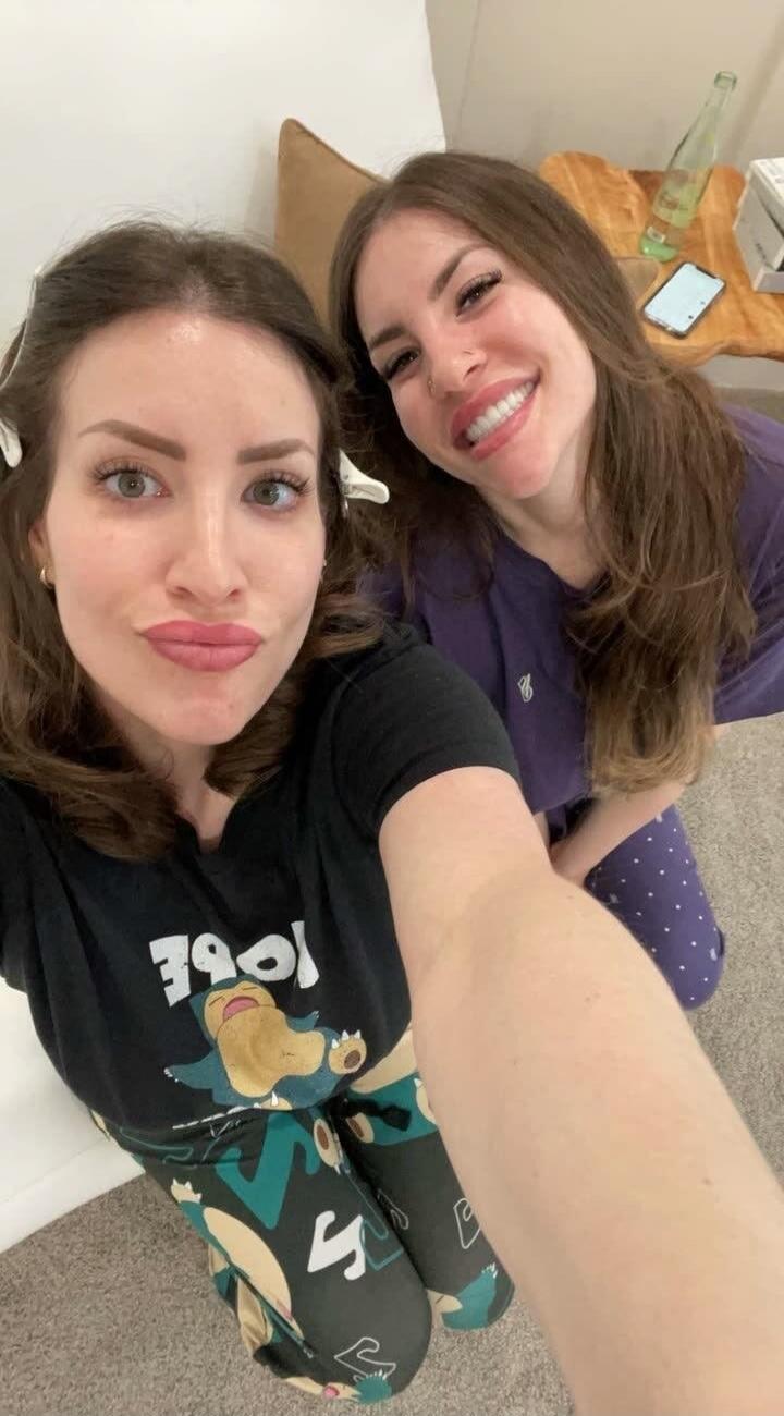 Two women taking a selfie. One woman is wearing a black t-shirt with a Snorlax character and the word 'LOVE' written on it, along with matching leggings. The other woman is wearing purple pajamas. They are smiling and posing for the camera.