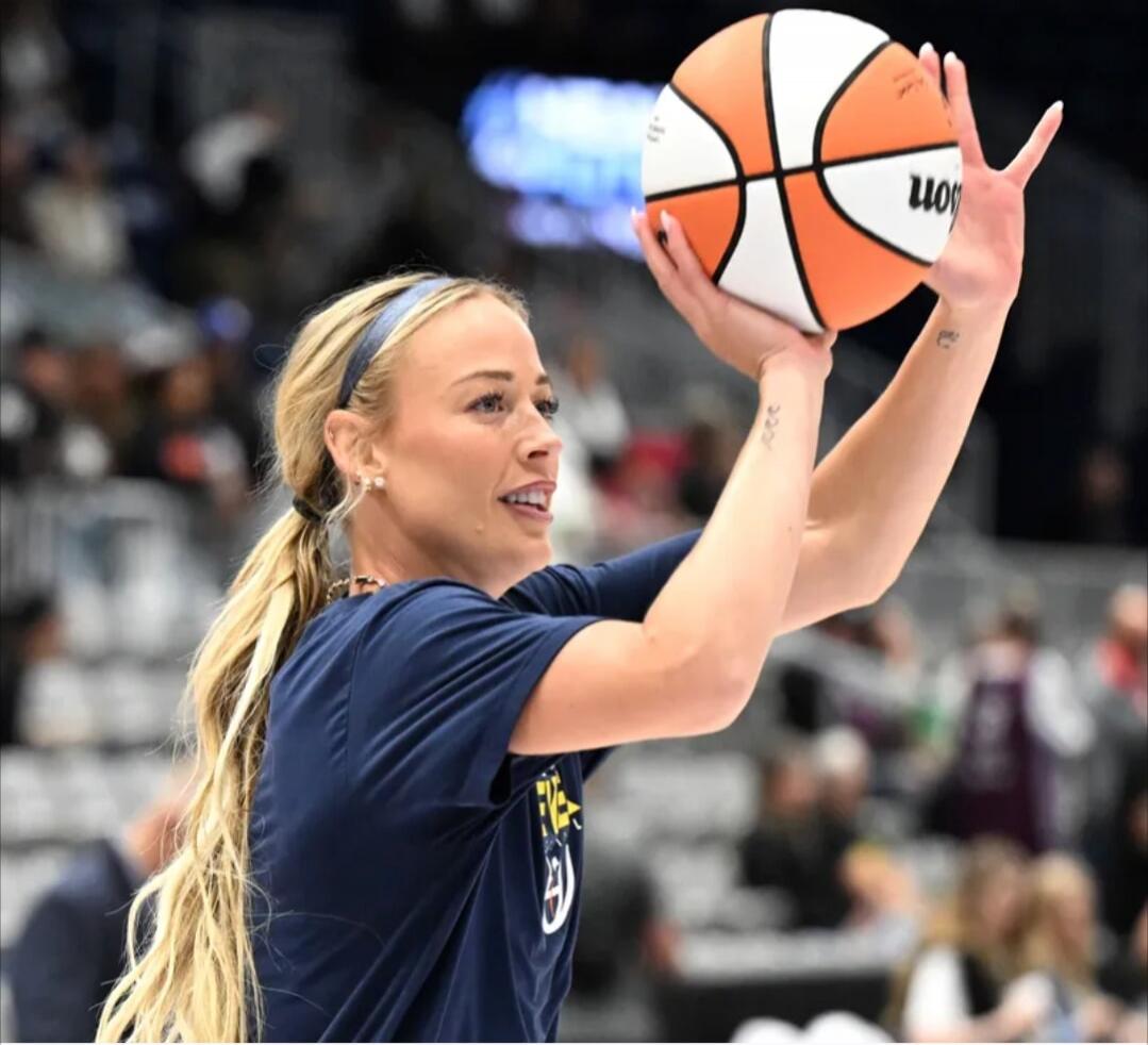 A woman holding a basketball. The brand 'Wilson' is visible on the ball.