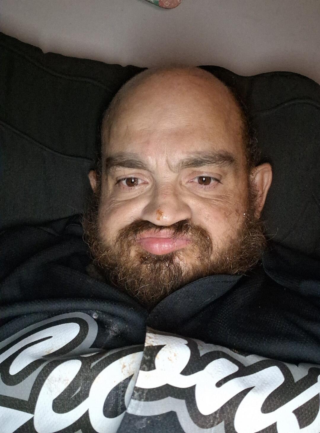 A man with a beard looking at the camera with a slightly pouting expression.