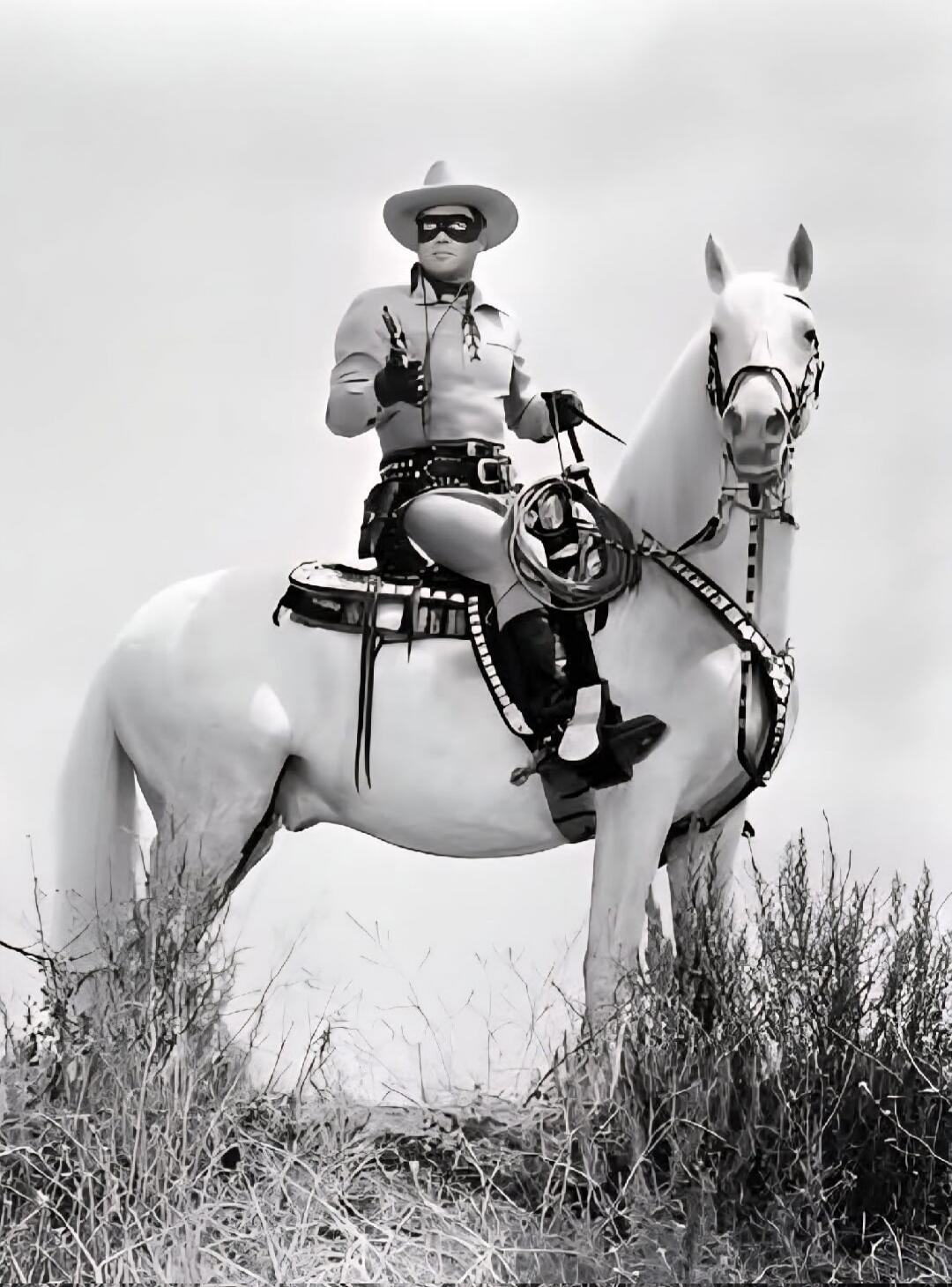 The Lone Ranger on his white horse, Silver. He is wearing his iconic mask and outfit, holding a pistol and a lasso.