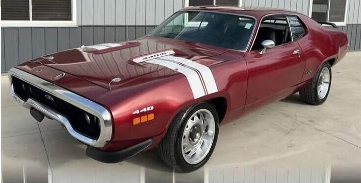 A classic red Plymouth GTX 440 muscle car with white racing stripes on the hood, featuring '440' and 'GTX' badges, and '440-6' on the hood scoop.