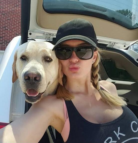 A woman taking a selfie with a dog in a car.