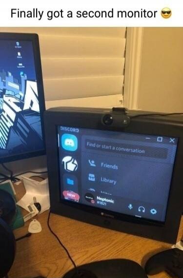 Finally got a second monitor 😎. The image shows a modern computer setup with an old CRT television used as a second monitor, displaying the Discord application. On the CRT screen, text like 'Find or start a conversation', 'Friends', 'Library', and a user 'Neptonic #1821' are visible. A webcam is mounted on top of the CRT TV.