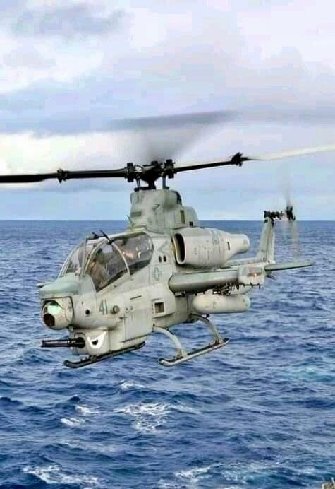 A military helicopter hovering over the ocean.