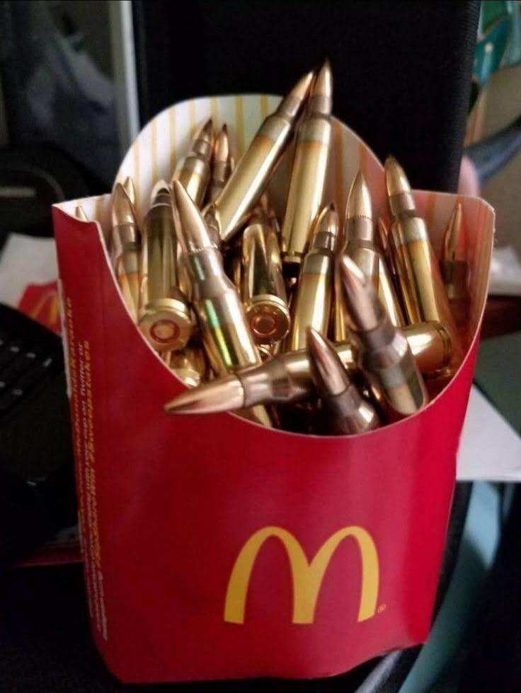 A McDonald's french fries container filled with numerous golden rifle cartridges.